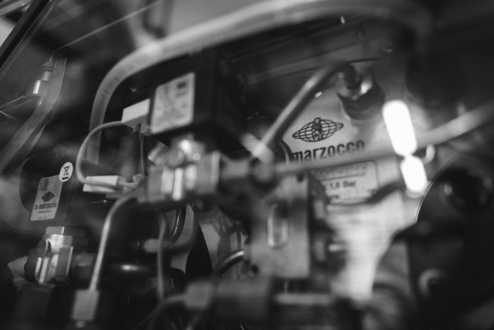 Inside an espresso machine. Solenoid valves, pipes, and the La Marzocco logo in the back