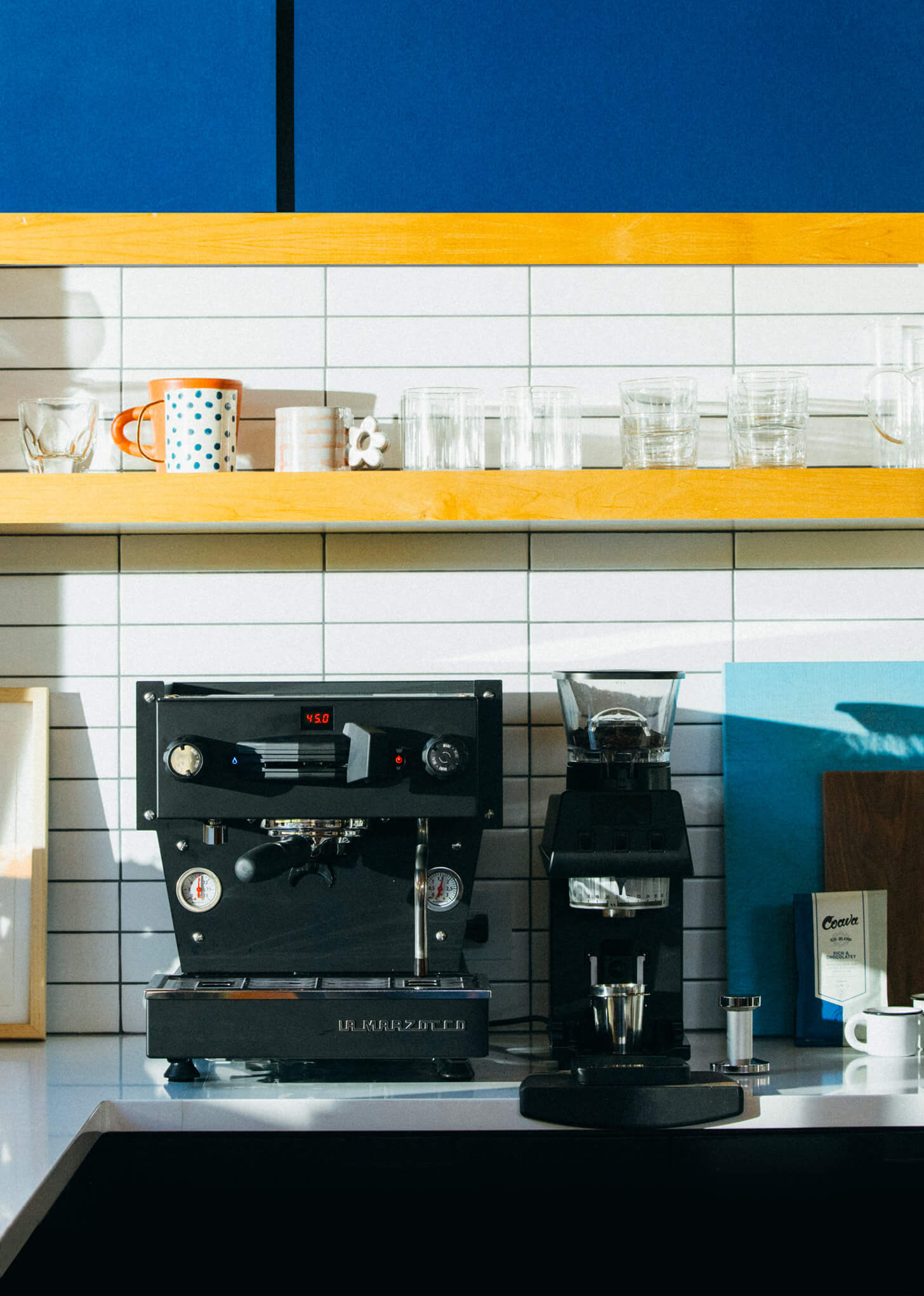 Black La Marzocco Linea Mini R espresso machine and black Pico coffee grinder on a white countertop