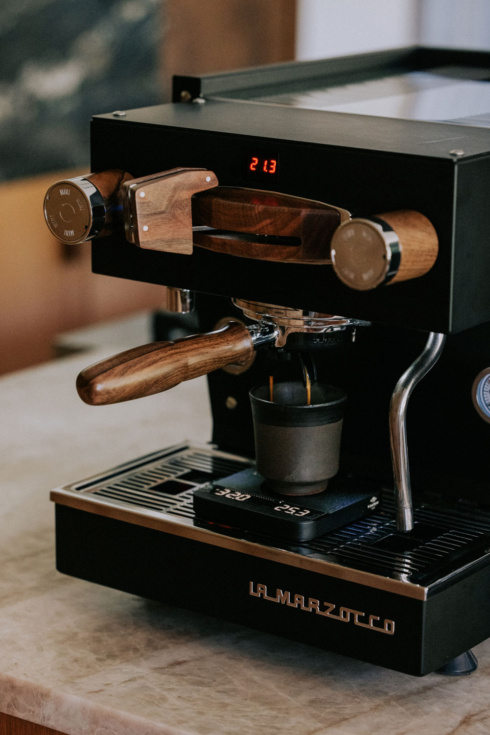 Closeup of Linea Mini with wooden details, brewing espresso.